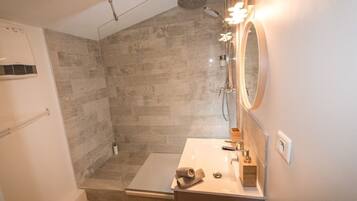 Une salle de bain moderne avec une douche, un lavabo et un miroir.