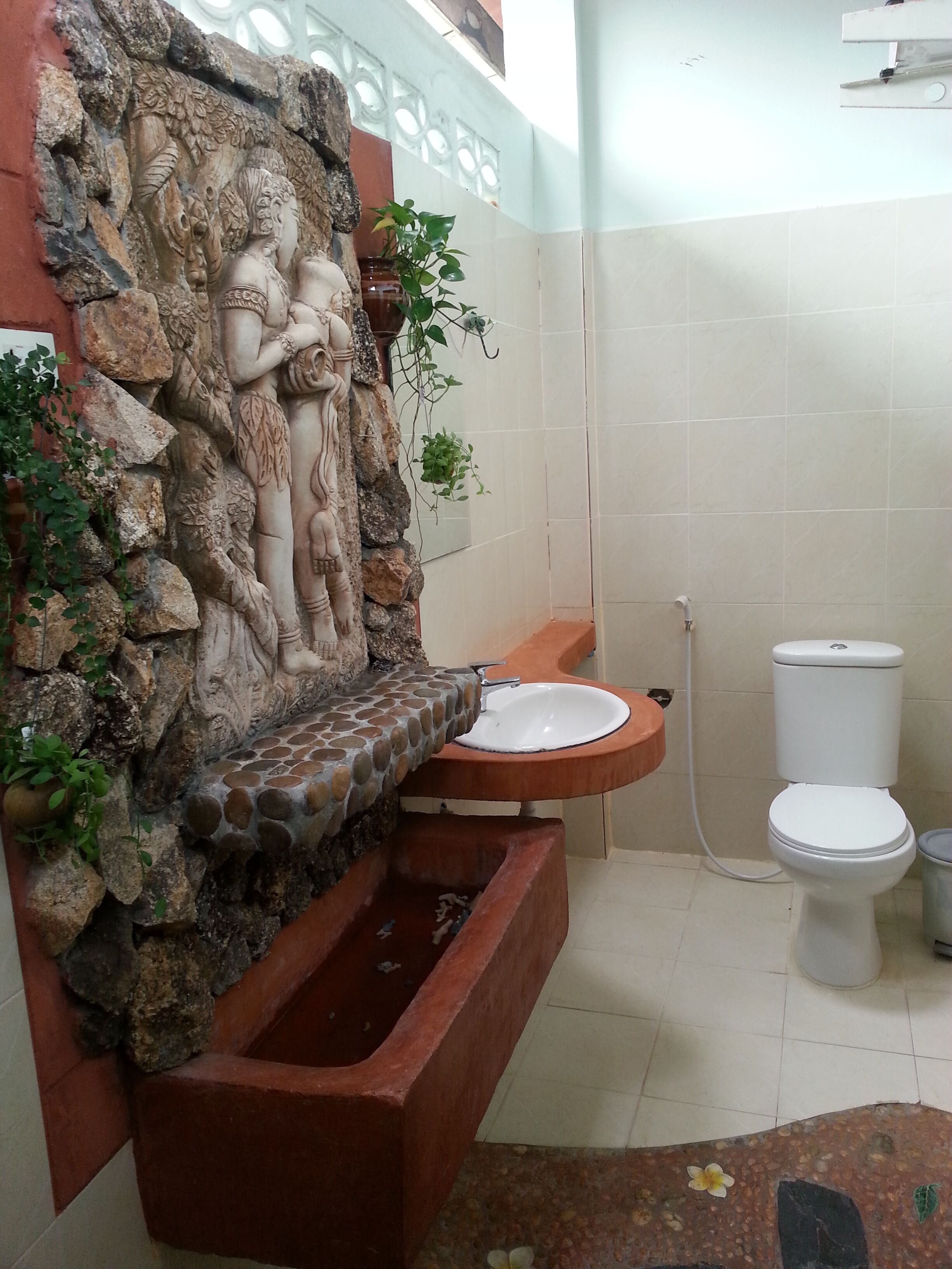 A bathroom with a stone wall, a sink, and a toilet.