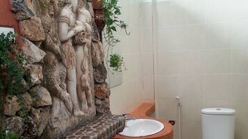 A bathroom with a stone wall, a sink, and a toilet.