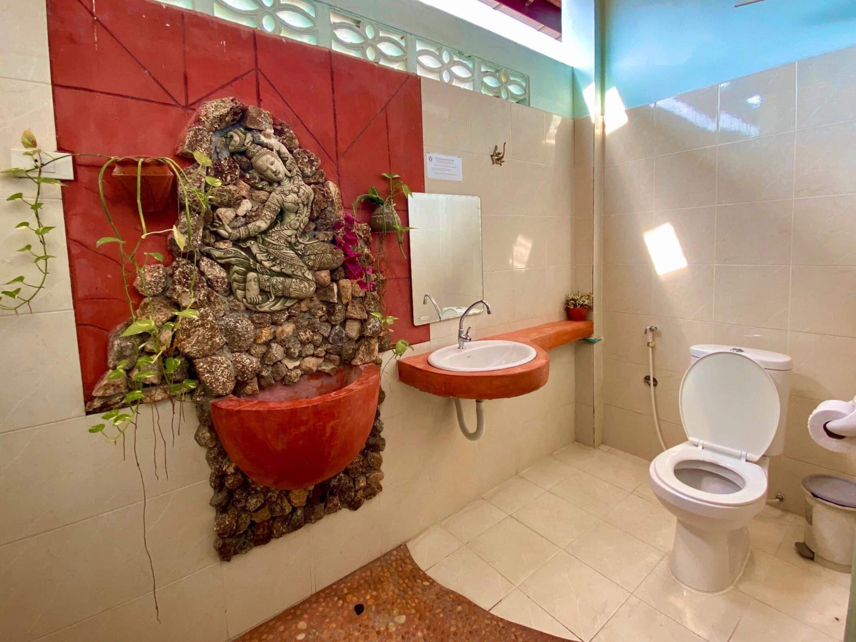A bathroom with a decorative rock wall, a sink, and a toilet.