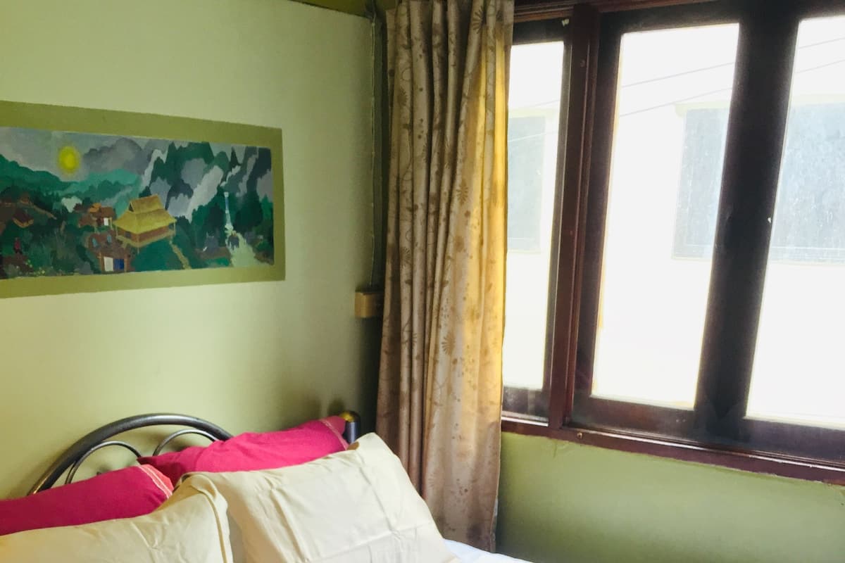Een bed met een witte deken, twee kussens en een rode handdoek.