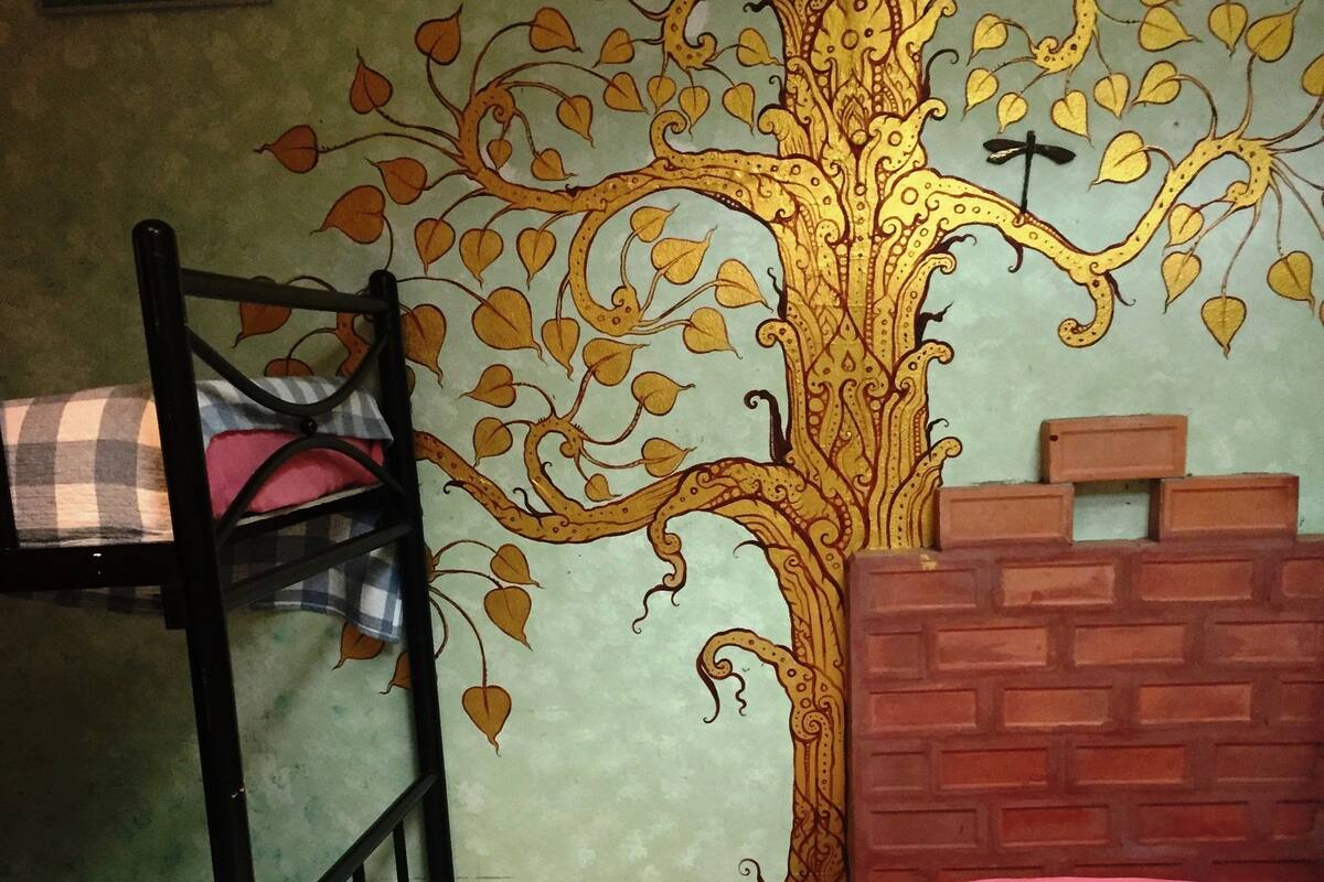 Een slaapkamer met stapelbed en een muurschildering van een boom.