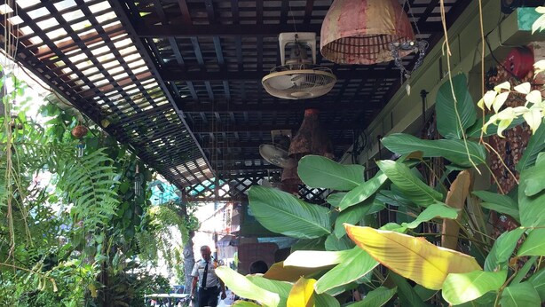 Une enseigne rustique en bois portant le nom « SHANTI LODGE » et ornée d’un motif décoratif en forme de flamme.