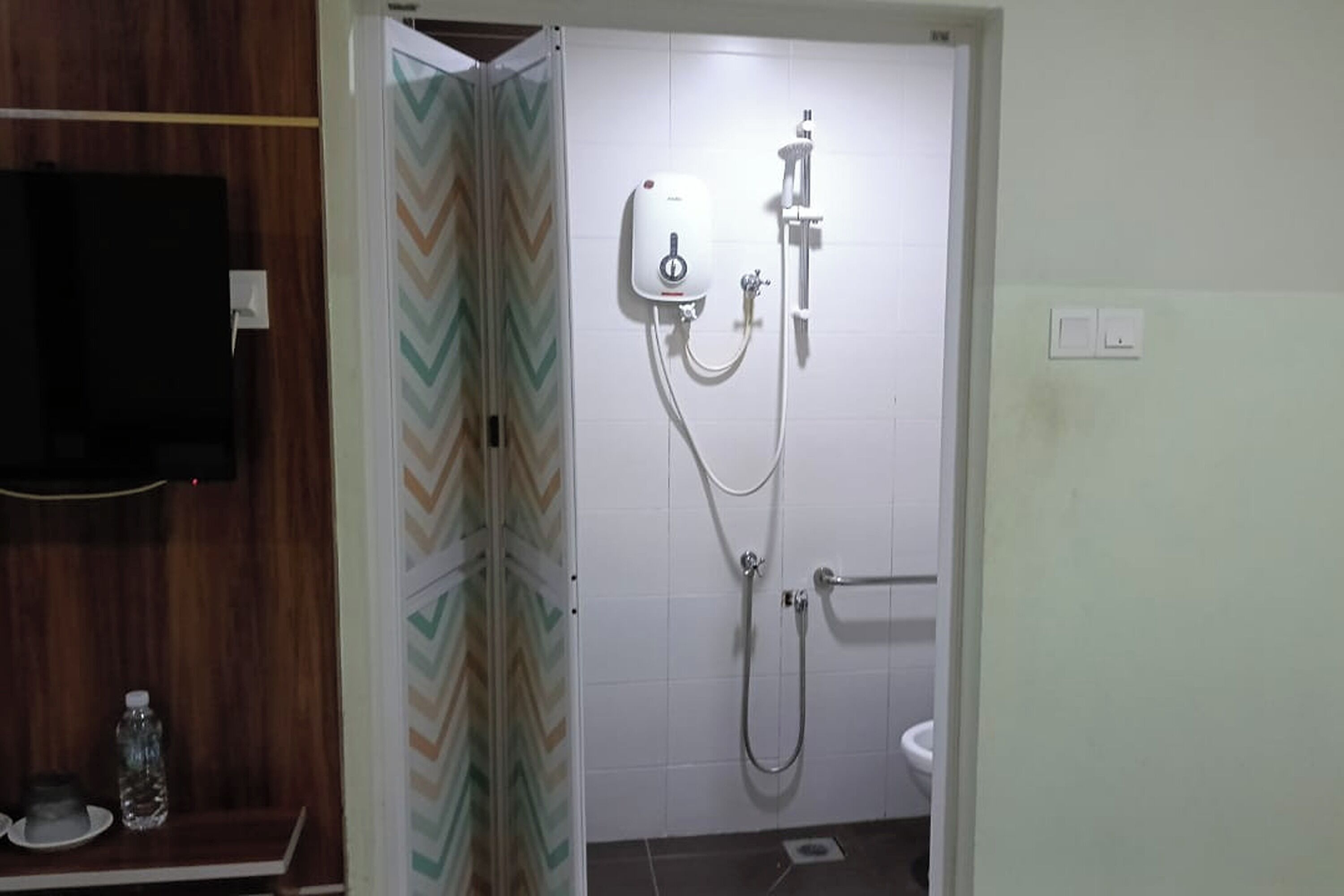 Een badkamer met douche, toilet en spiegel.