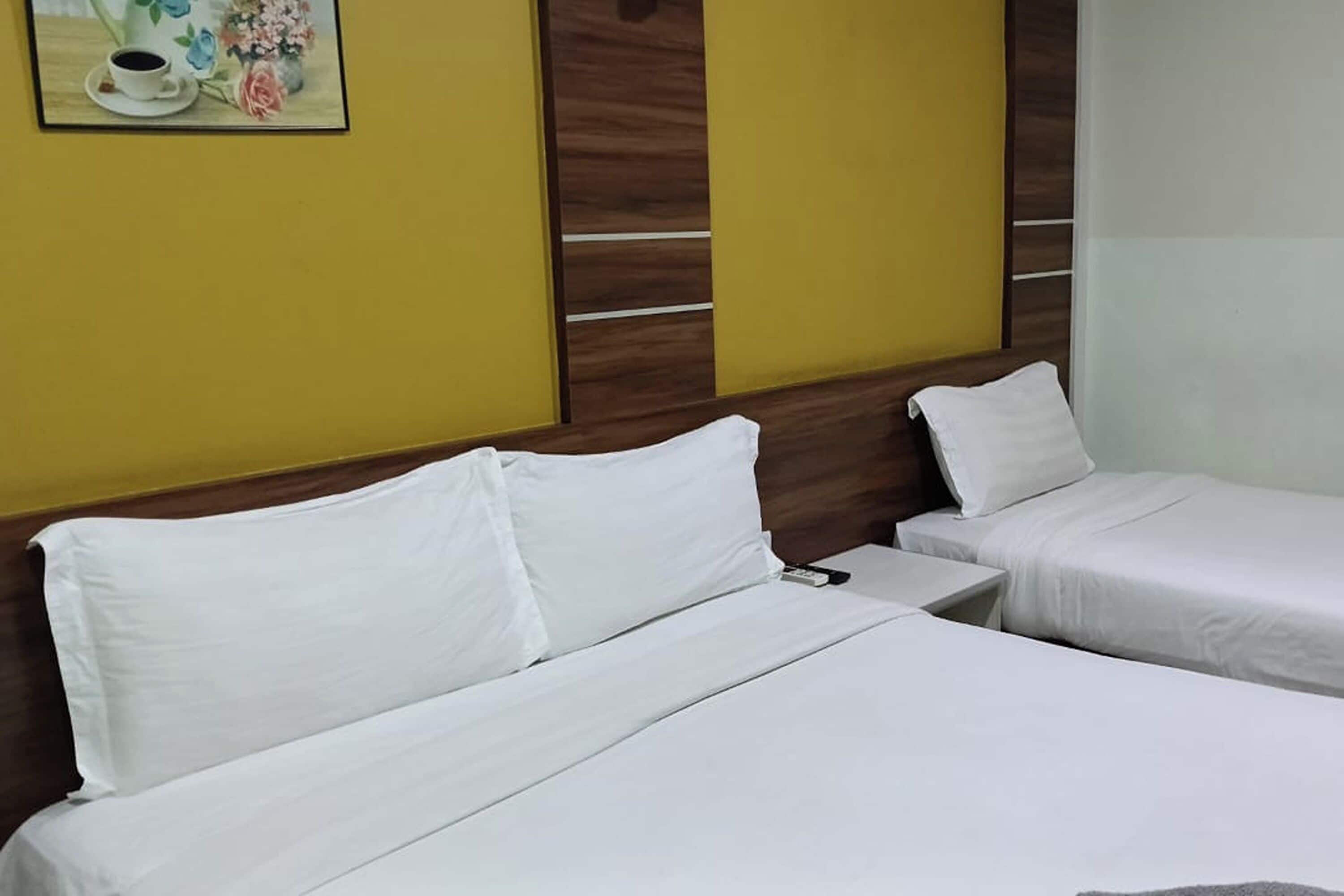 Habitació d'hotel amb dos llits, un capçal de fusta, una petita taula de nit i una fotografia emmarcada a la paret.