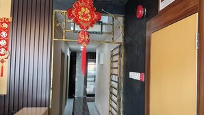A hallway with a decorative red hanging ornament, a wooden door, and a metal gate. - Golden Night Hotel Sunway (Subang Jaya)