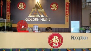 A reception desk with a sign reading 'GOLDEN NIGHT' and a large golden triangle logo. - Golden Night Hotel Sunway (Subang Jaya)