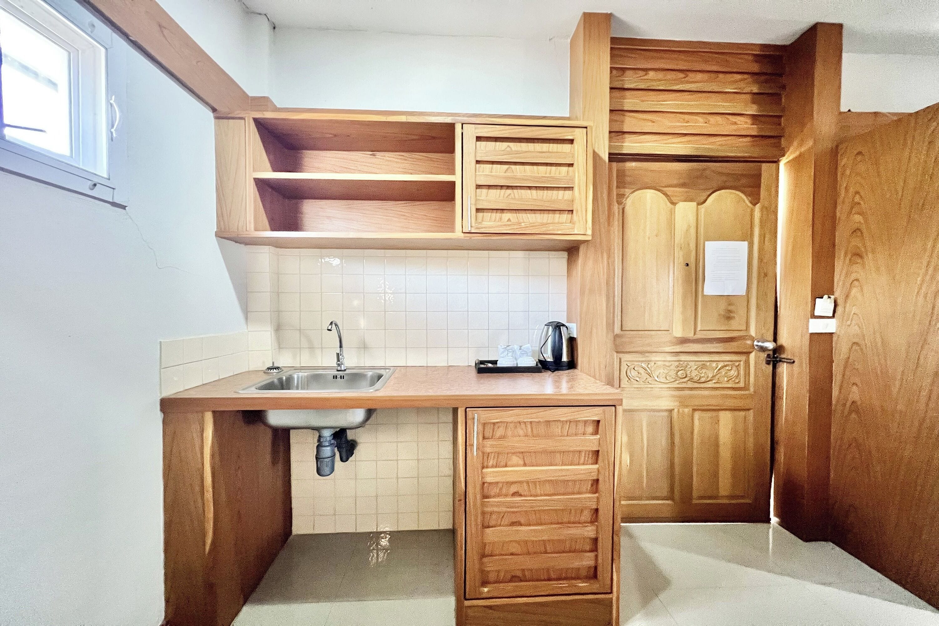 Cocina compacta con armarios de madera, un lavamanos y una ventana.