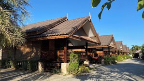 A row of traditional wooden houses with tiled roofs, arranged along a paved street.