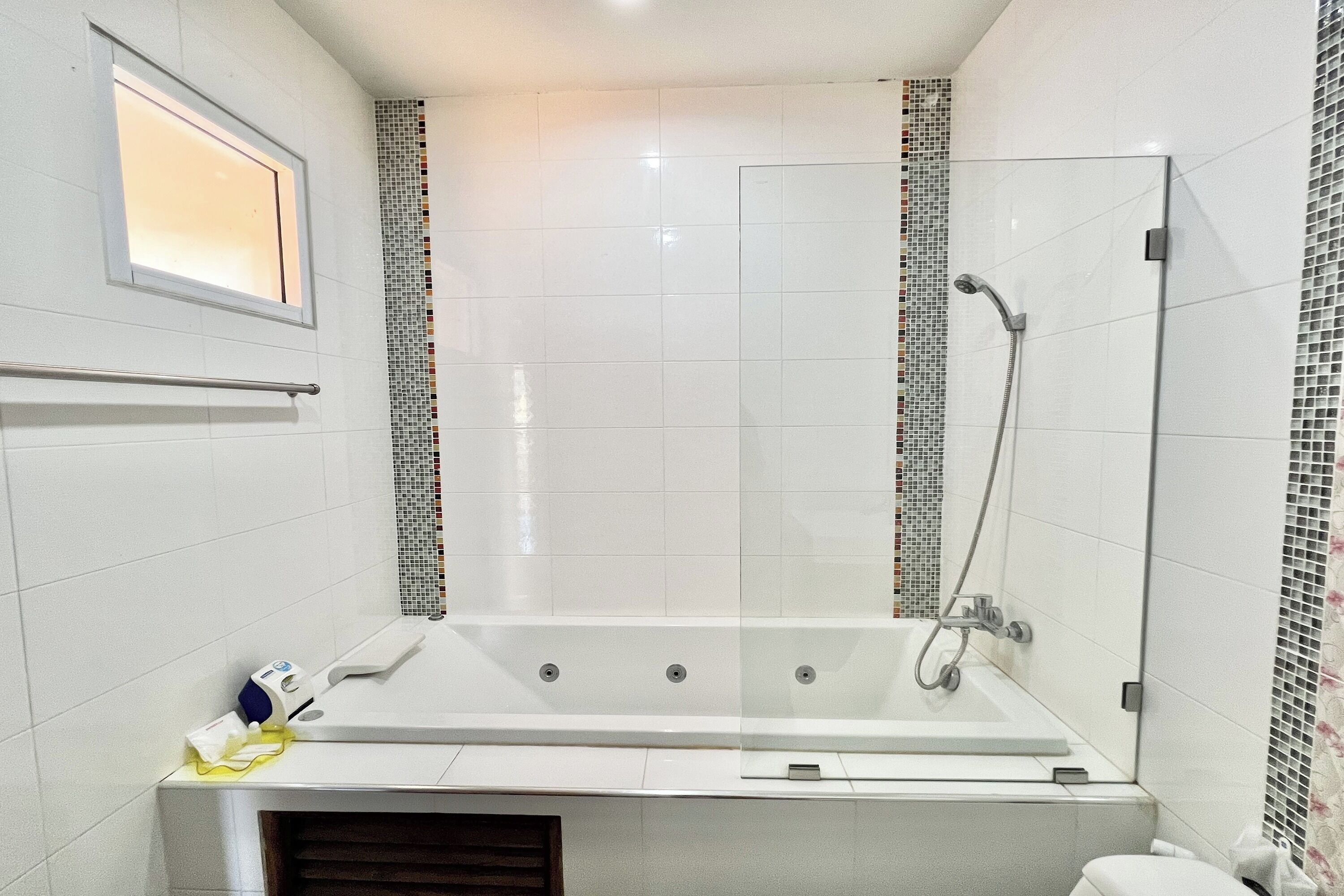 A modern bathroom with a glass-enclosed shower, a large bathtub, and a small window.