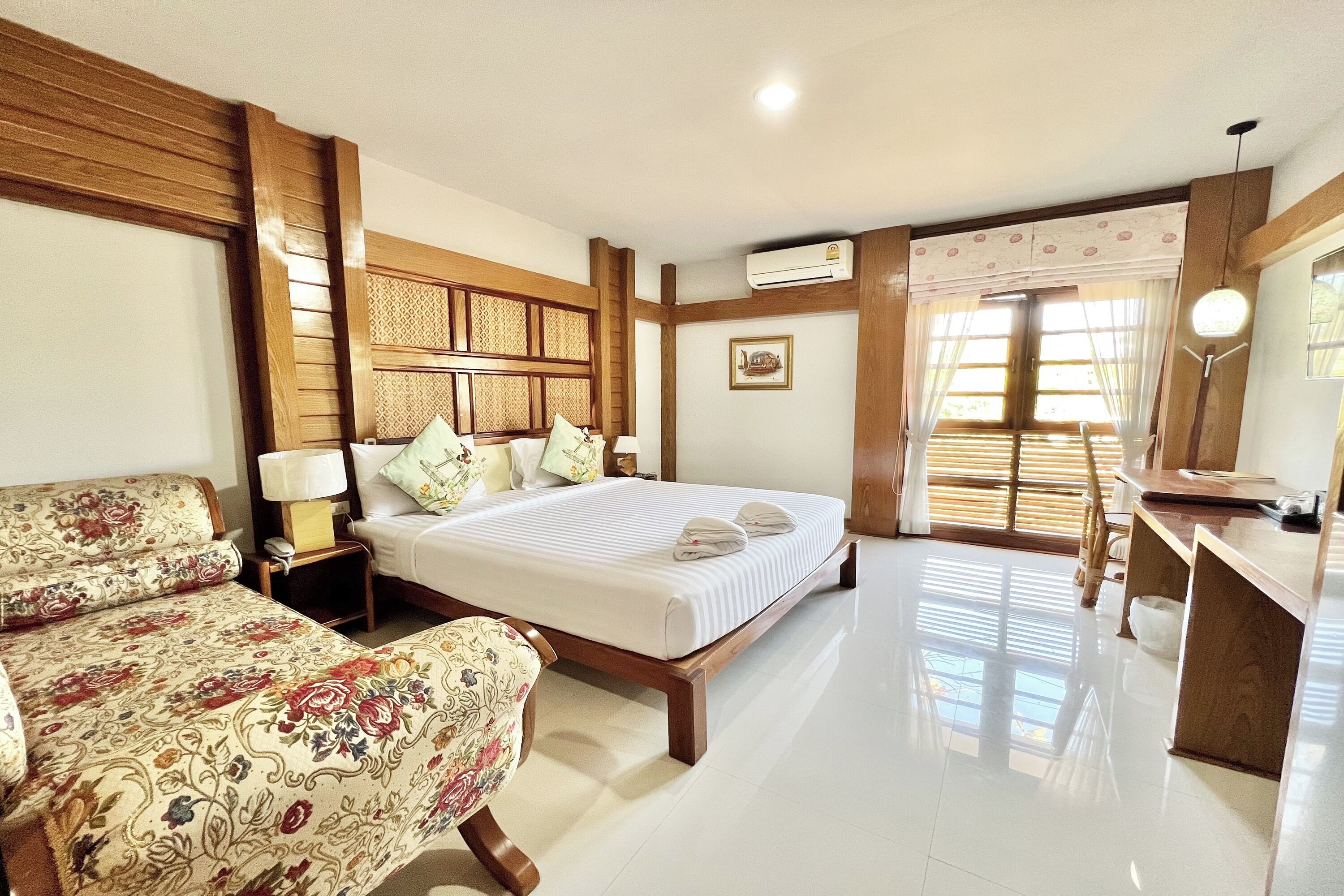 A hotel room with a large bed, a smaller bed, a desk, and a chair.