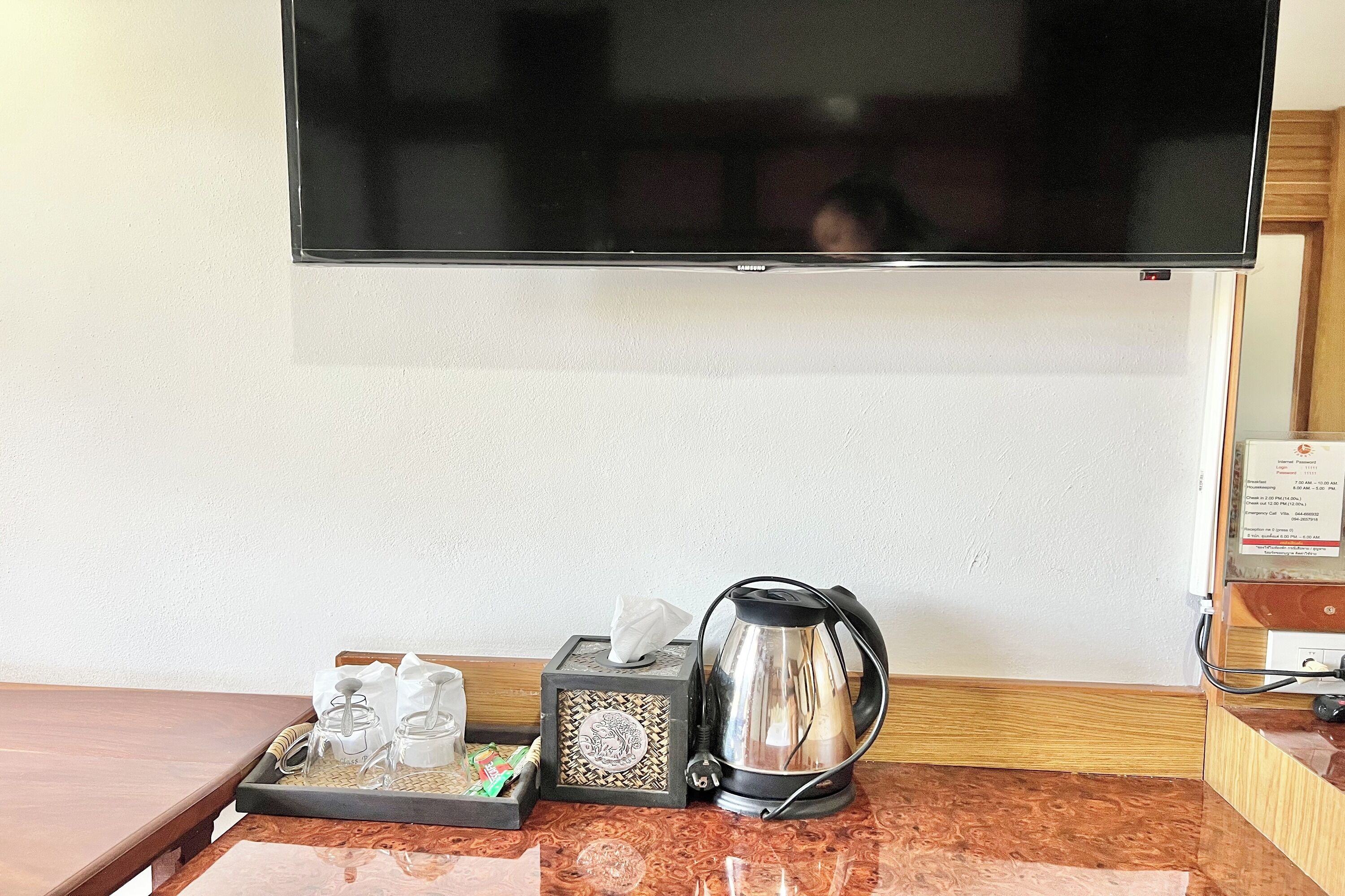 Habitación de hotel con televisor de pantalla plana montado en la pared, una bandeja con servicio de té y una cafetera sobre la encimera.