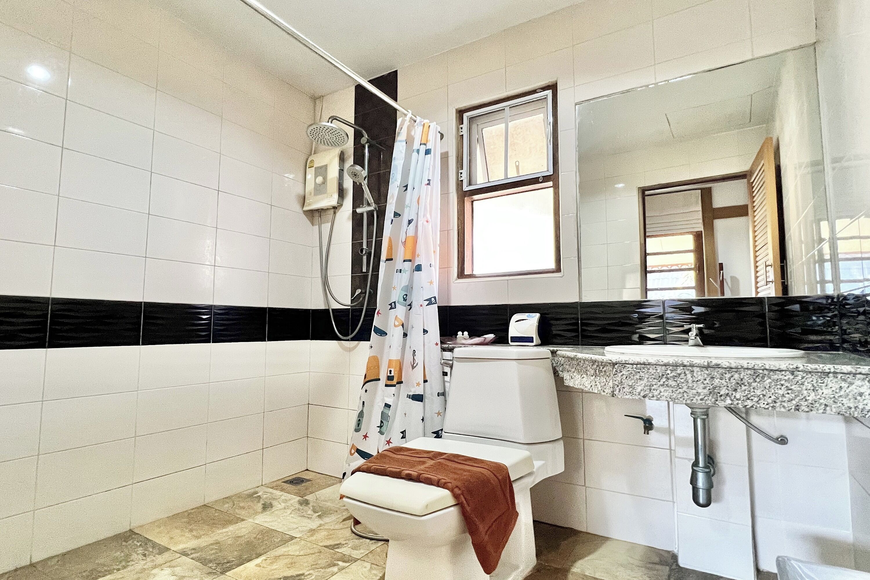 A bathroom with a shower, toilet, sink, and mirror.