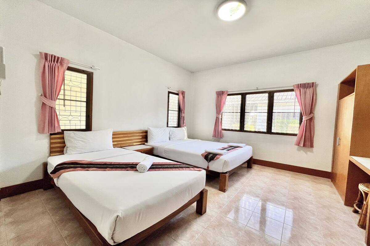 Una habitación de hotel con dos camas individuales, un armario de madera y una ventana con cortinas.