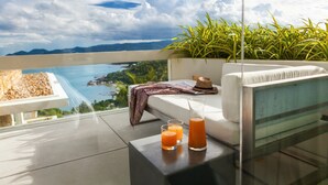 A balcony with a white sofa, a patterned throw, a straw hat, and two glasses of orange juice. - Villa Anavaya (Koh Samui)