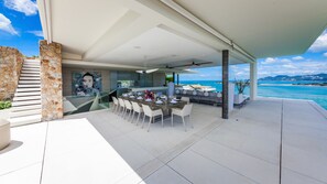 A modern outdoor dining area with a view of the ocean, a stone staircase, and a mural on the wall. - Villa Anavaya (Koh Samui)