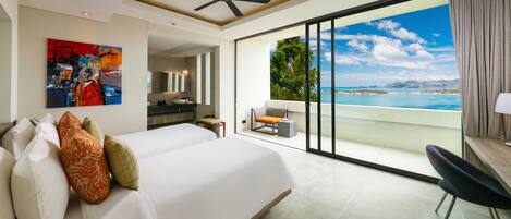 A modern hotel room with a large bed, a desk, and a balcony with a sea view.
