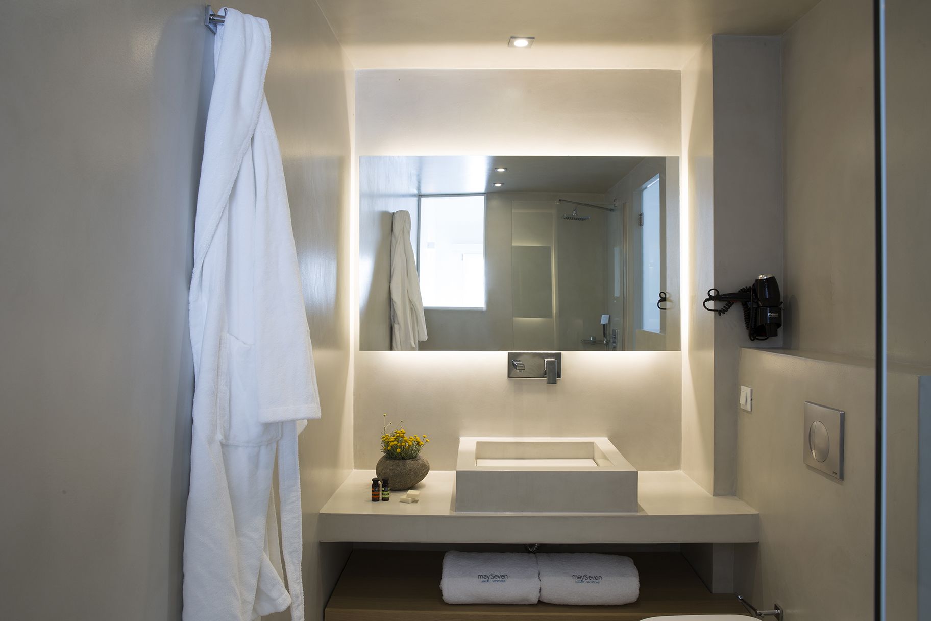 Un bagno moderno con un lavandino bianco, uno specchio grande e un portascopevoli.