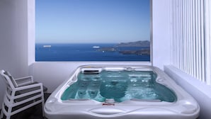 A hot tub with a view of the ocean and a chair. - May Seven Santorini (Santorini)