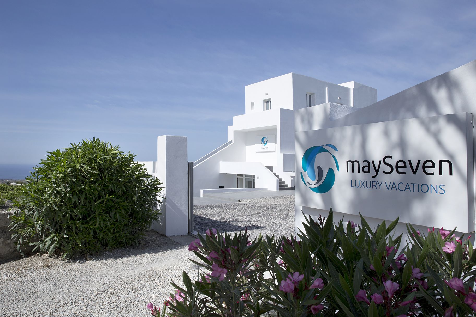 A modern white building with a logo for 'maySeven Luxury Vacations'.
