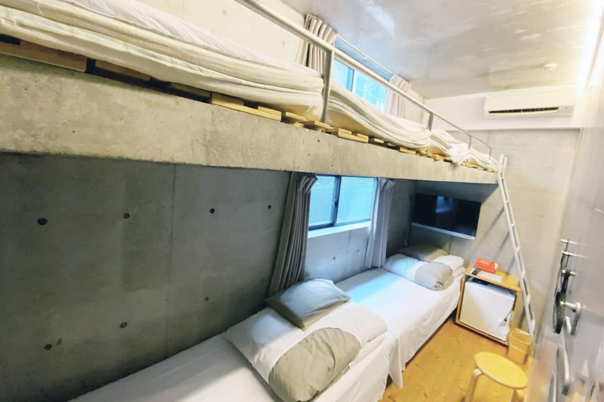 Une chambre avec un lit superposé, un petit bureau et un tabouret.