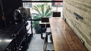 A modern kitchen with a wooden countertop, a built-in fan, and a view of the street through a large window. - Kangaroo Hotel (Tokyo)