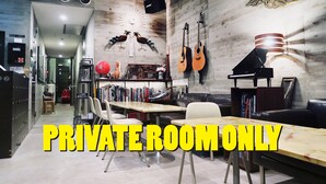 A private room with a wooden table, chairs, a sofa, a bookshelf, and a wall-mounted lamp. - Kangaroo Hotel (Tokyo)