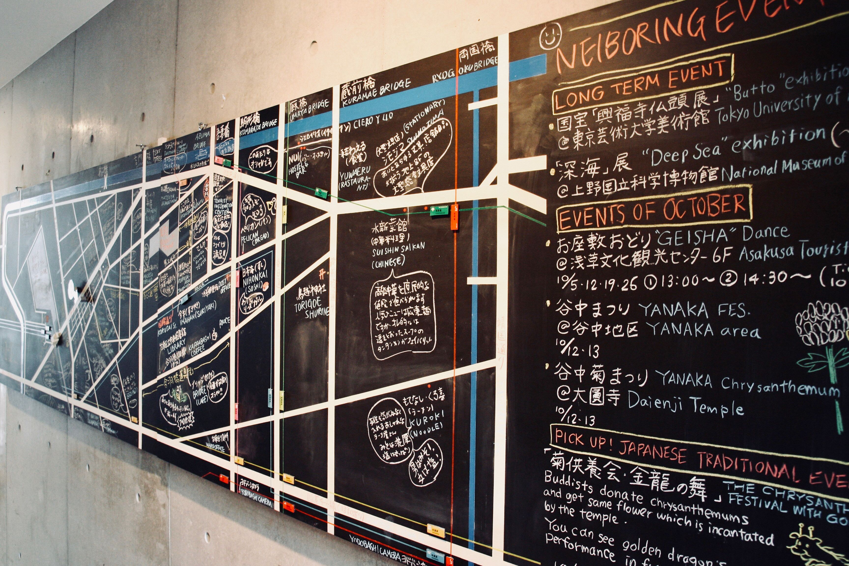 A wall with chalkboard-style signs listing events and locations, including a dance event and a chrysanthemum festival.