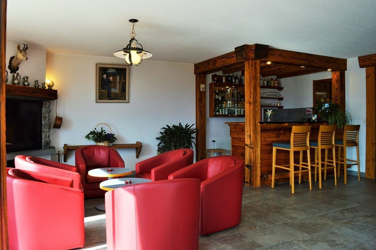 Una sala de estar acogedora con sofás de cuero rojo, una chimenea, una zona de bar de madera y un cuadro en la pared.
