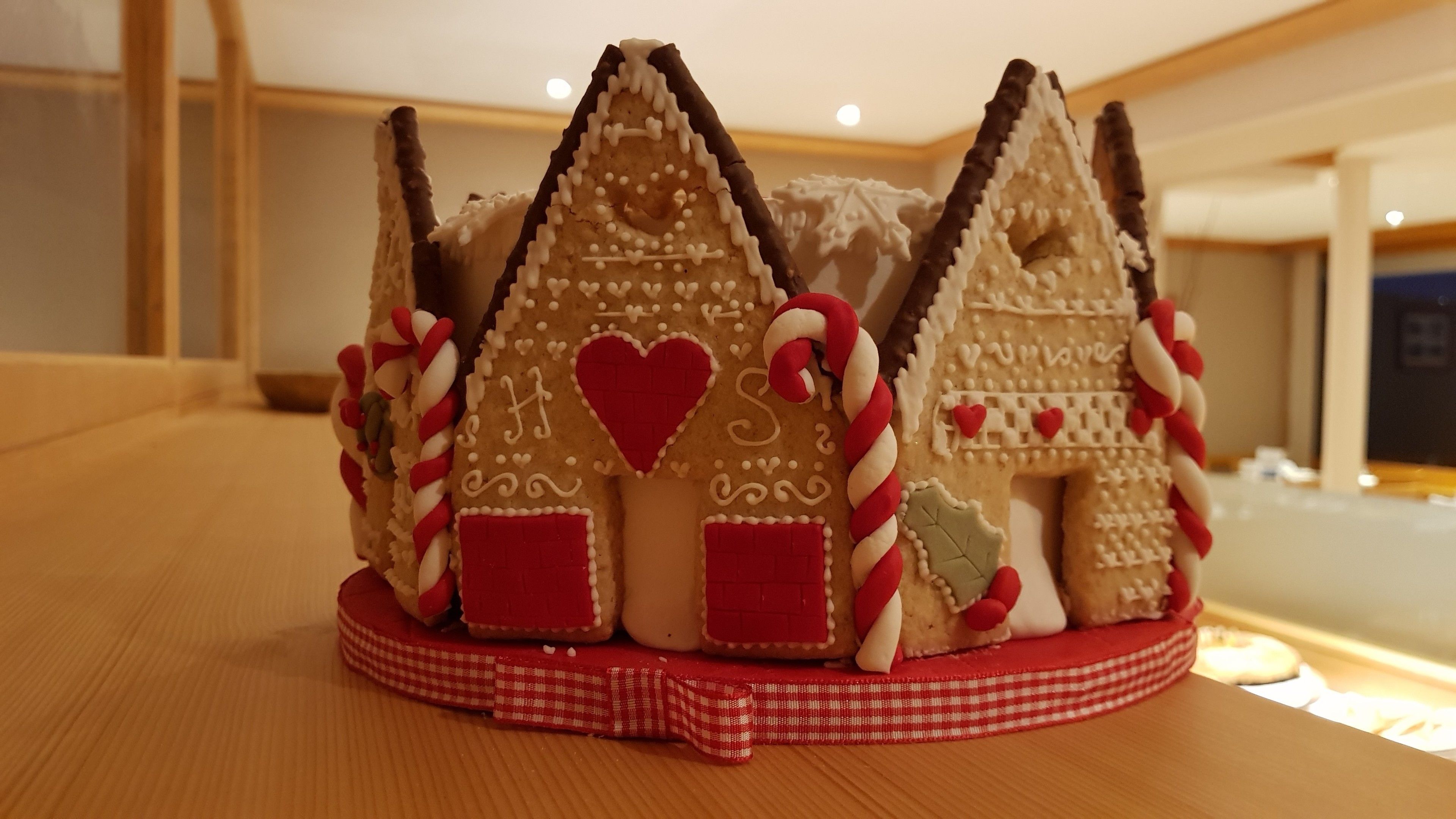 Una casa de jengibre con adornos de bastón de caramelo sobre una mesa.