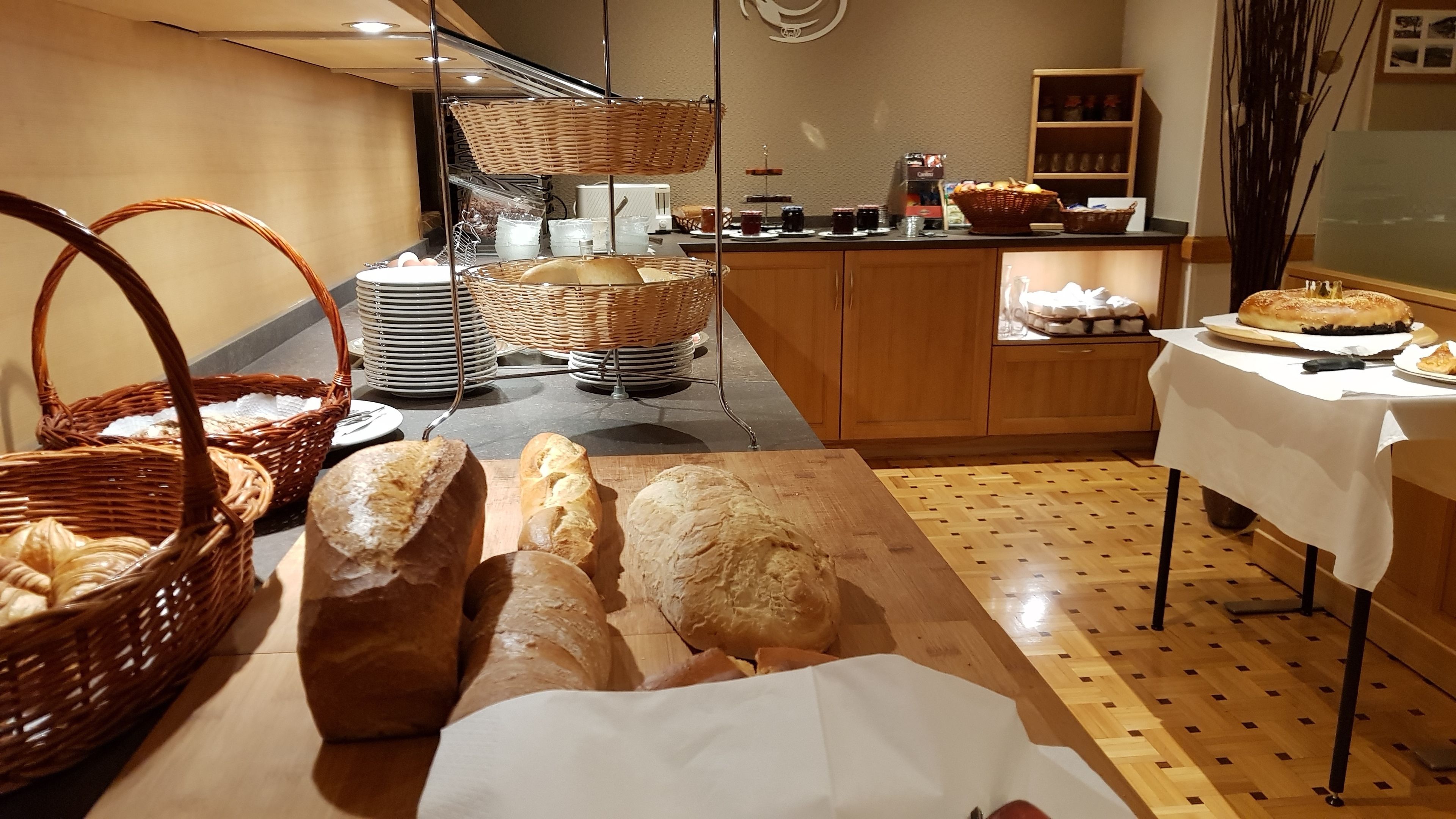 A bakery counter with various breads and pastries, baskets, and a coffee machine.