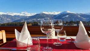 A table with three wine glasses and napkins, set against a backdrop of snow-capped mountains and a clear blue sky. - Hôtel Splendide (Crans-Montana)
