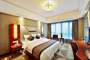 A hotel room with a large bed, a desk, a chair, a nightstand, and a window with curtains. - Excemon Cixi Guomai Hotel (Ningbo)