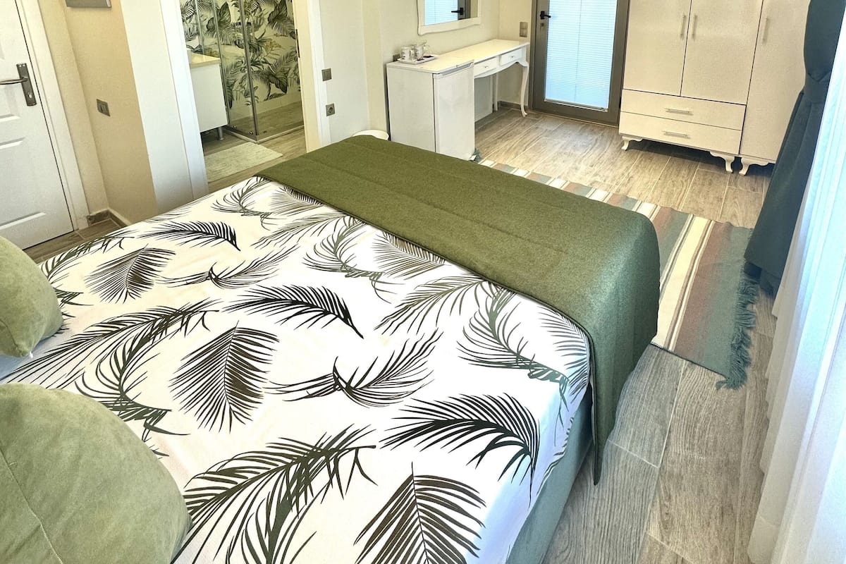 A bedroom with a bed, a TV, a desk, and a wardrobe.