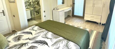 A bedroom with a bed, a TV, a desk, and a wardrobe.