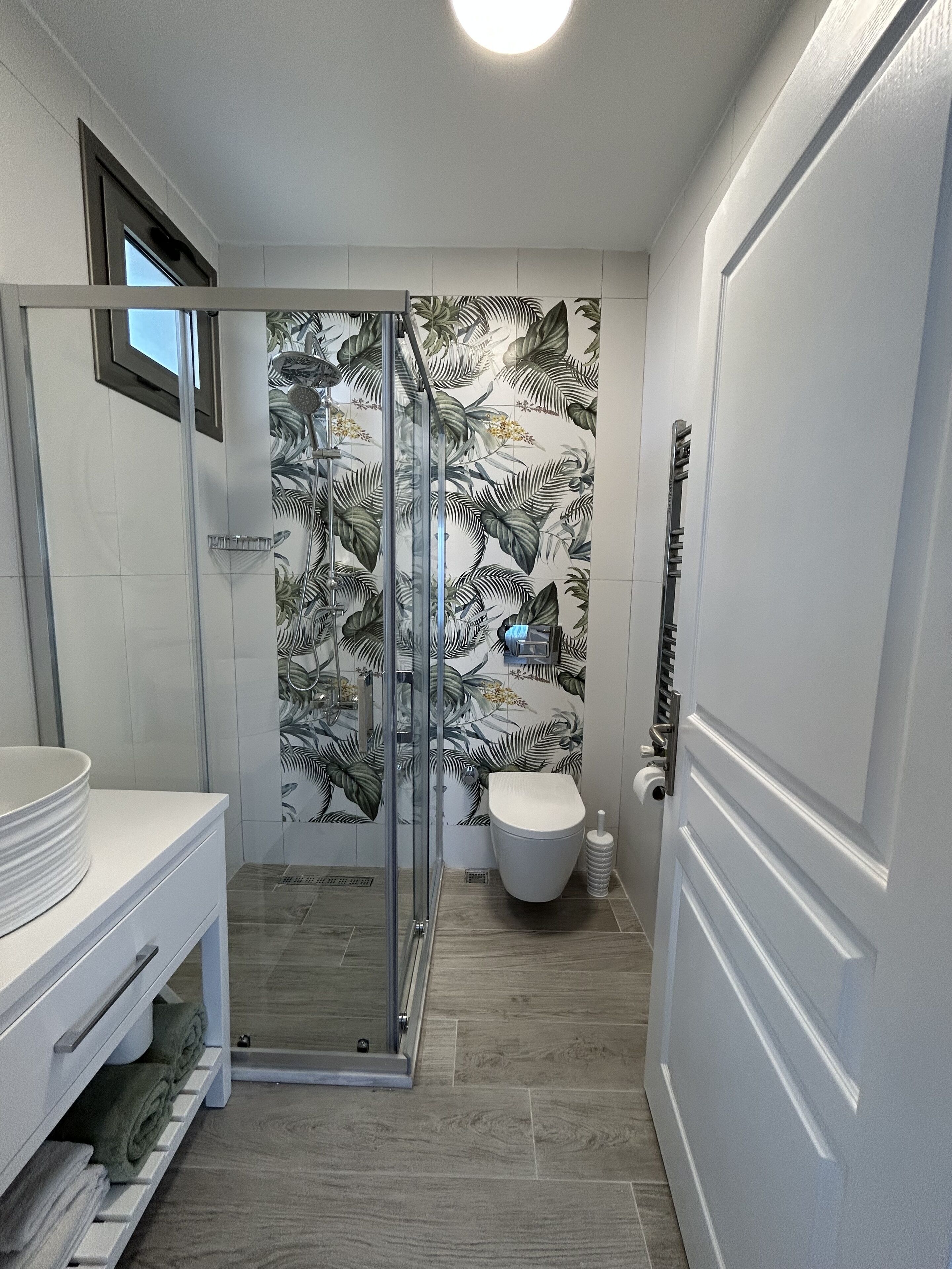 Un baño con cabina de ducha de vidrio, inodoro e lavabo con tocador.