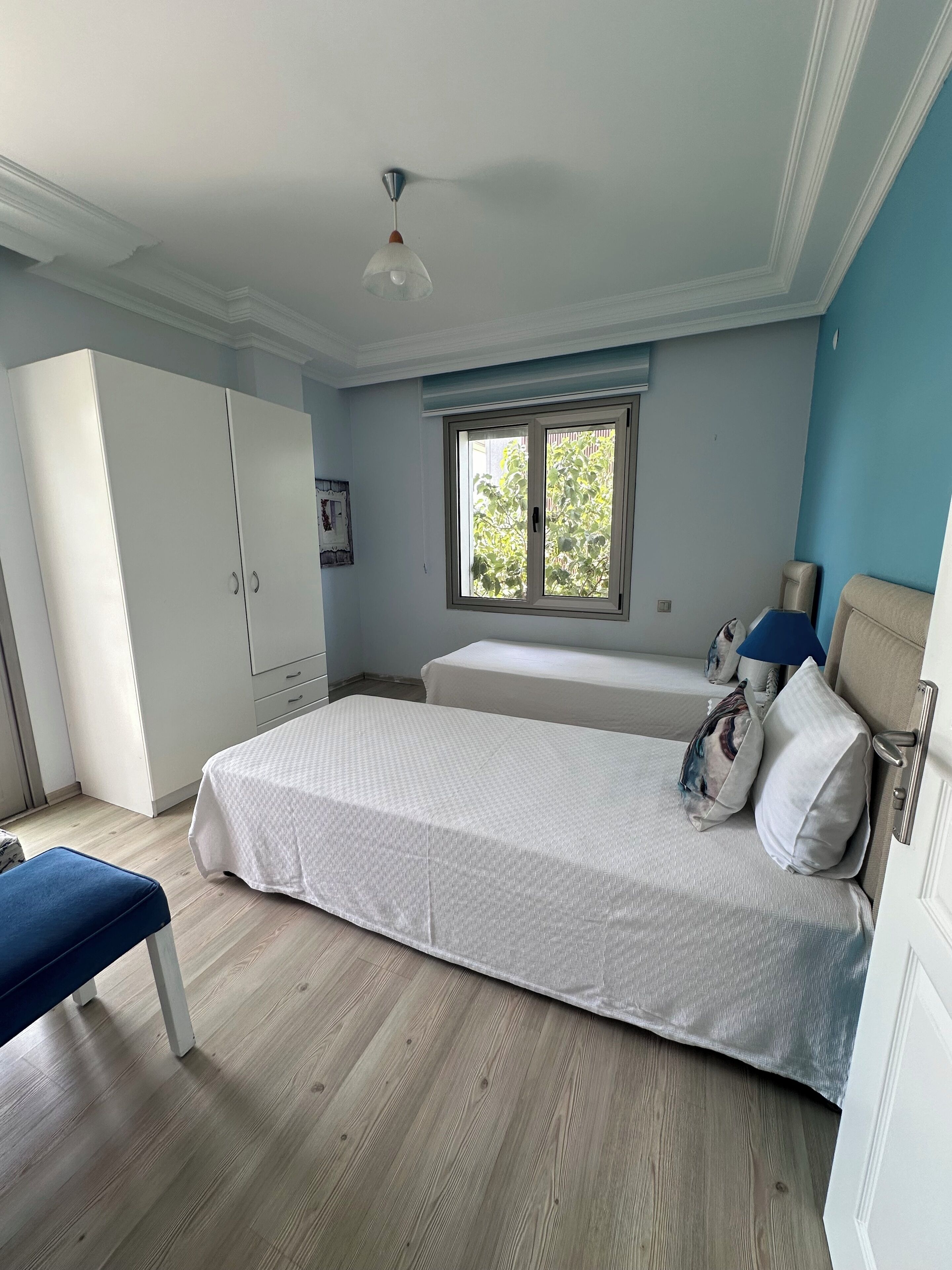 Un dormitorio con cama, ventana, armario y una banca.