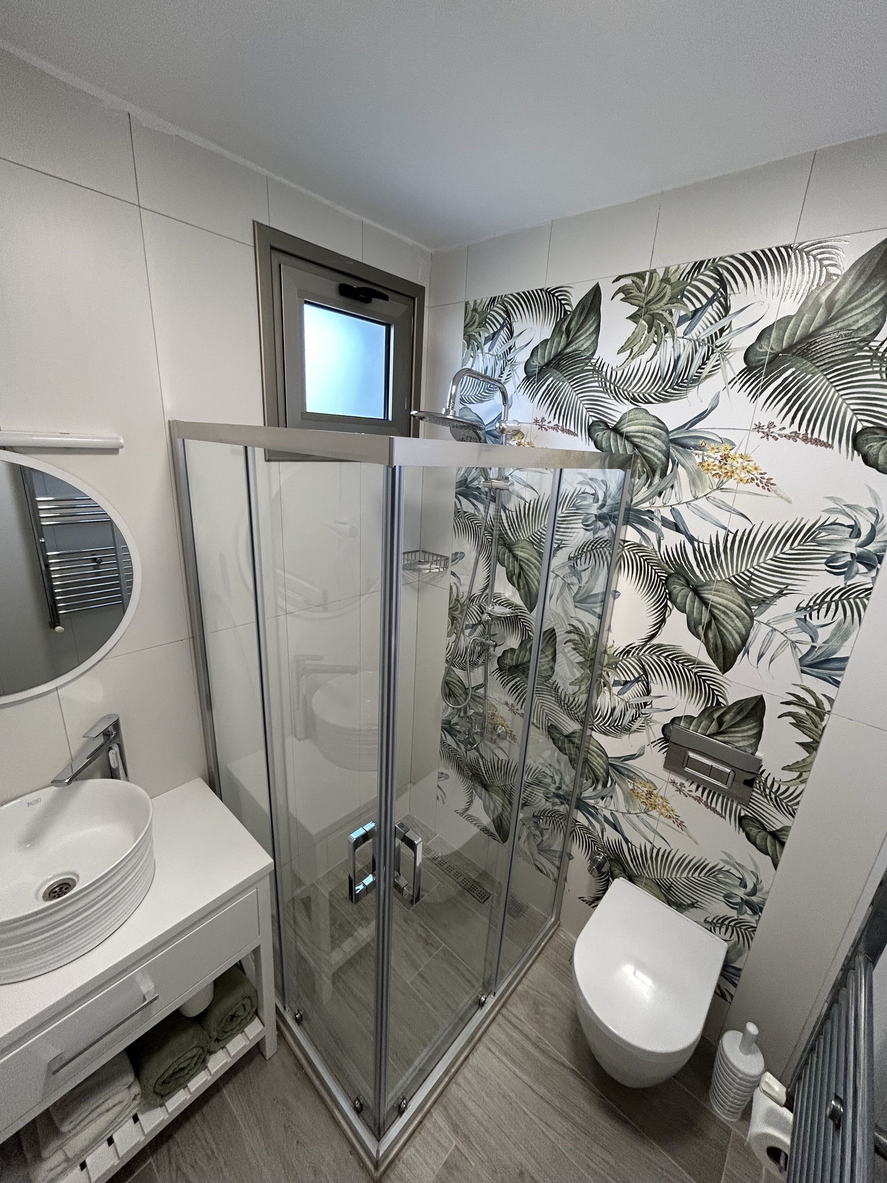 Un baño con cabina de ducha de vidrio, inodoro y lavamanos.