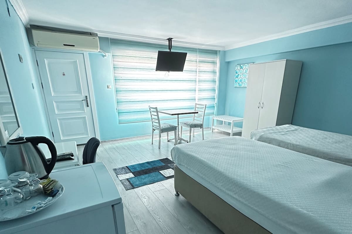 A hotel room with a bed, a desk, a chair, a TV, and a wardrobe.