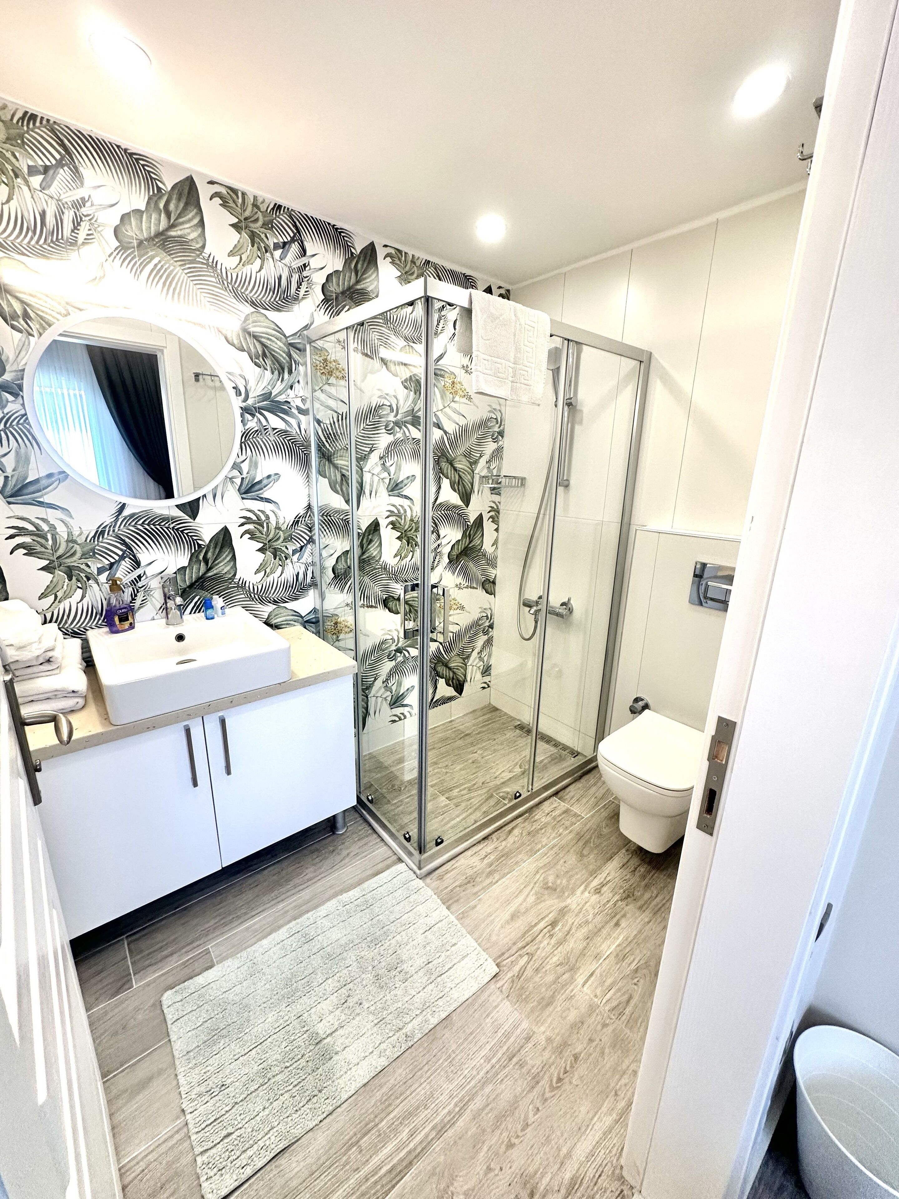 A modern bathroom with a glass shower enclosure, a white sink, and a toilet.