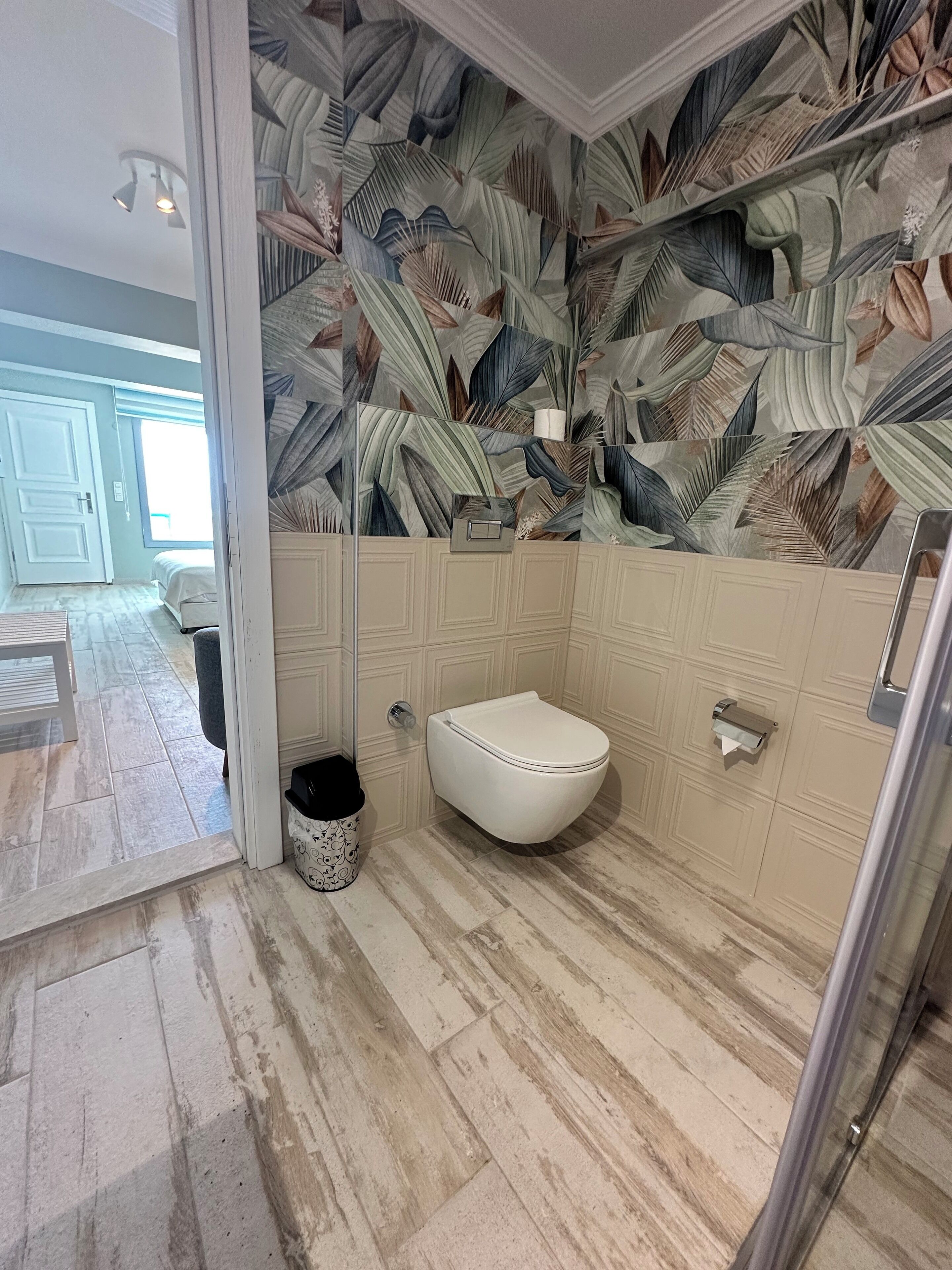 A bathroom with a white toilet, a shower area, and a patterned wall.