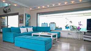 A modern living room with a teal sofa set, a white coffee table, and a TV on a stand. - Fener Hotel Cafe & Kahvalti (Cesme)