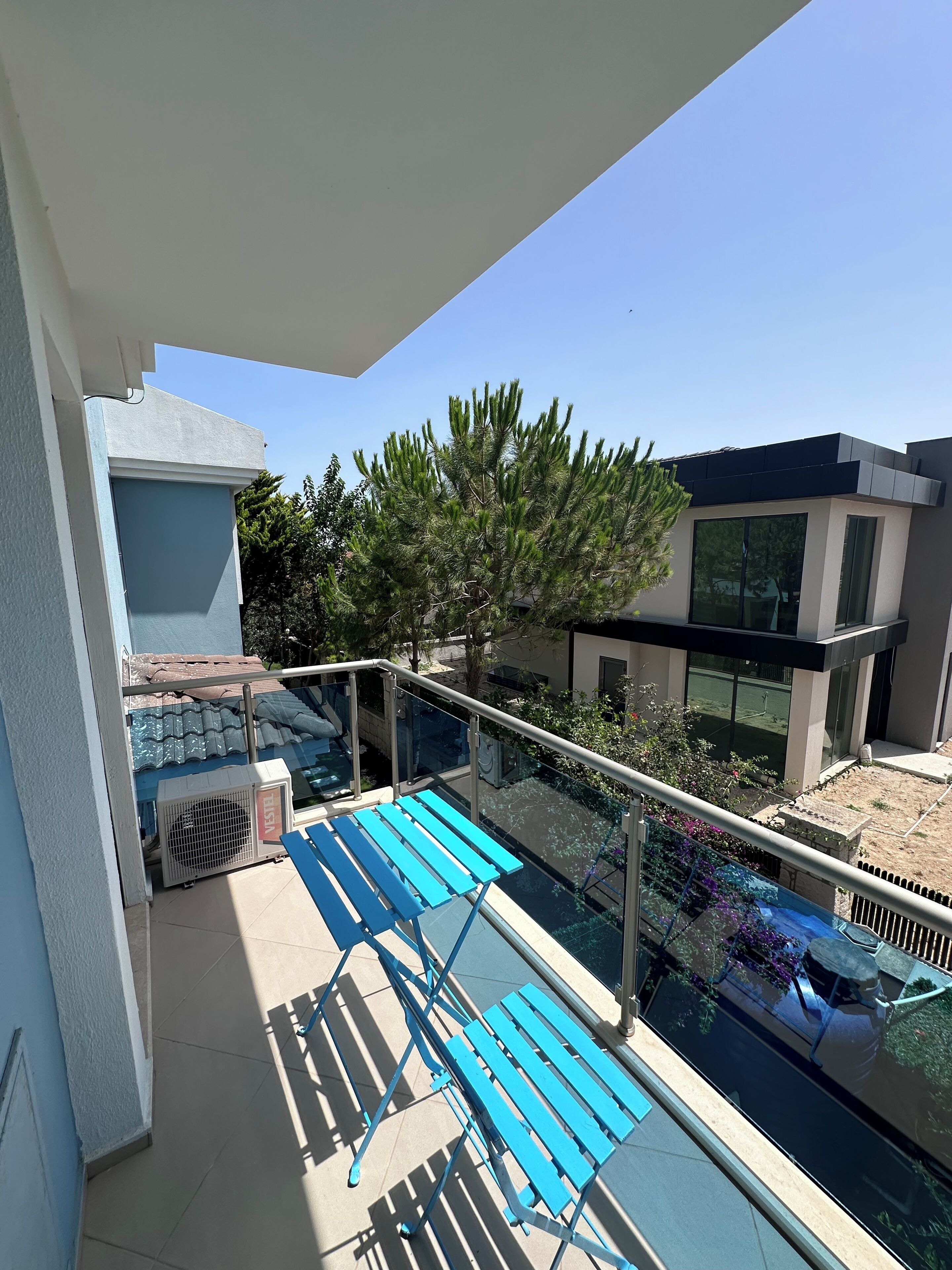 Un balcone con piscina, poltrone da relax blu e un edificio moderno sullo sfondo.