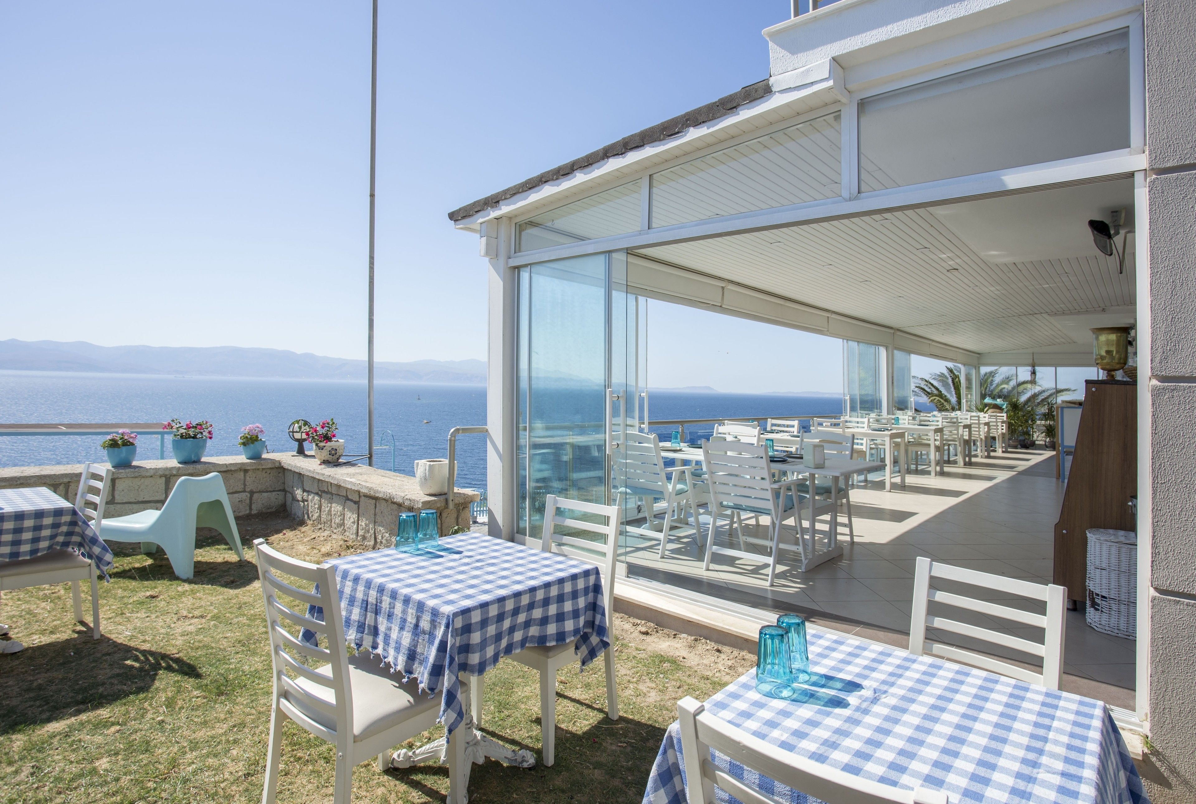 An outdoor patio with tables and chairs, overlooking a body of water.