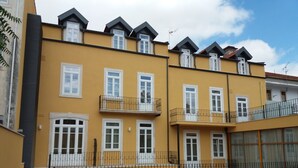 A yellow multi-story residential building with balconies, a wooden deck, and a green lawn. - Hotel Ibn-Arrik  (Coimbra)