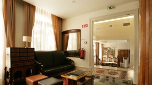 A hotel lobby with a leather sofa, a coffee table, a fireplace, and a red carpet. - Hotel Ibn-Arrik  (Coimbra)