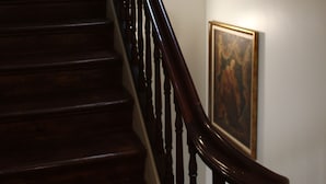 A wooden staircase with a handrail, a framed painting on the wall, and a light fixture above the staircase. - Hotel Ibn-Arrik  (Coimbra)