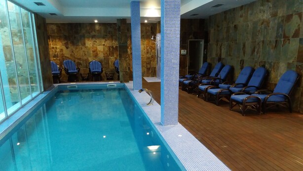 An indoor swimming pool with blue chairs and a tiled wall. - Hotel Ibn-Arrik  (Coimbra)