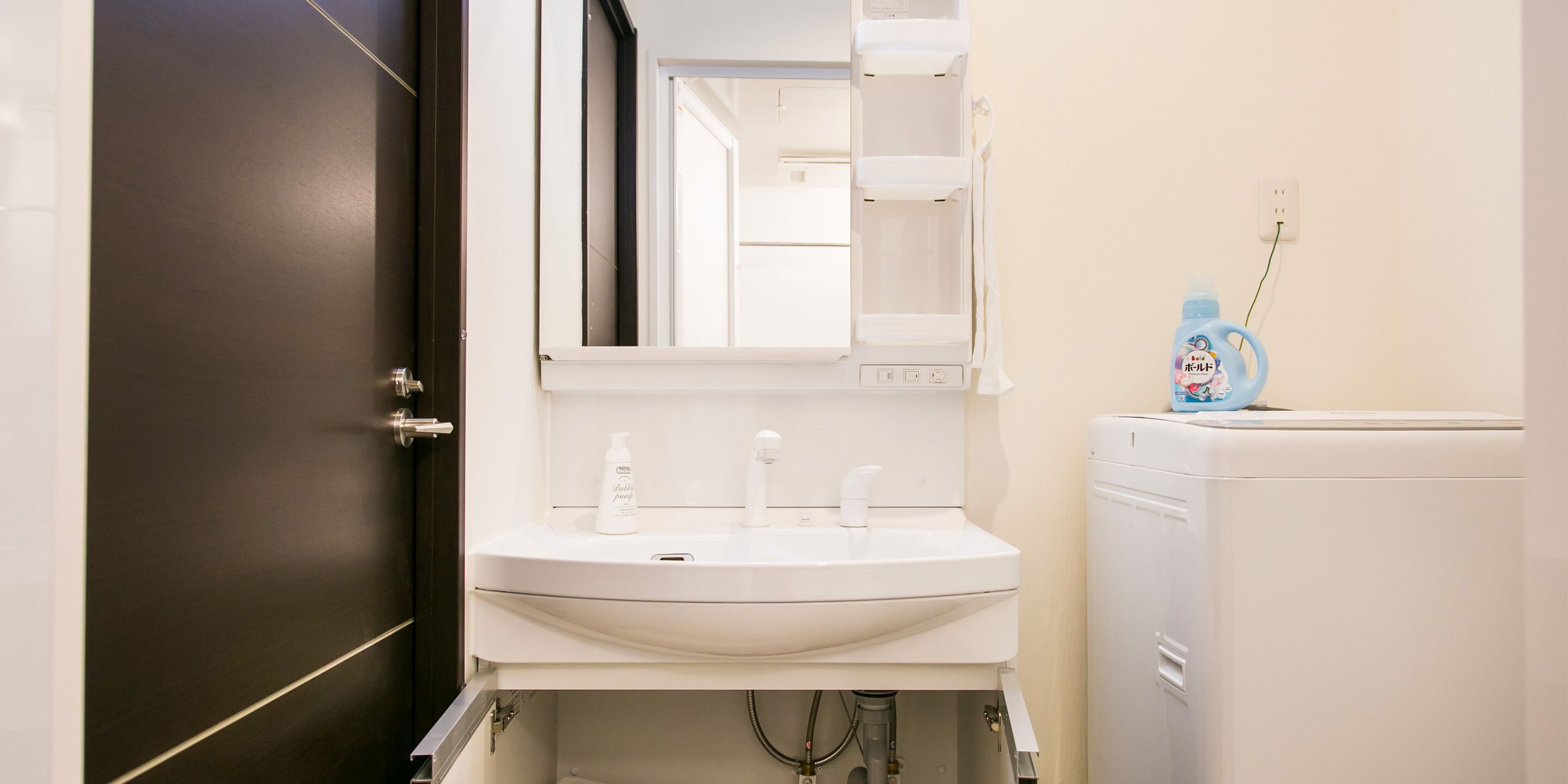 A bathroom with a white sink, mirror, and a white washing machine.