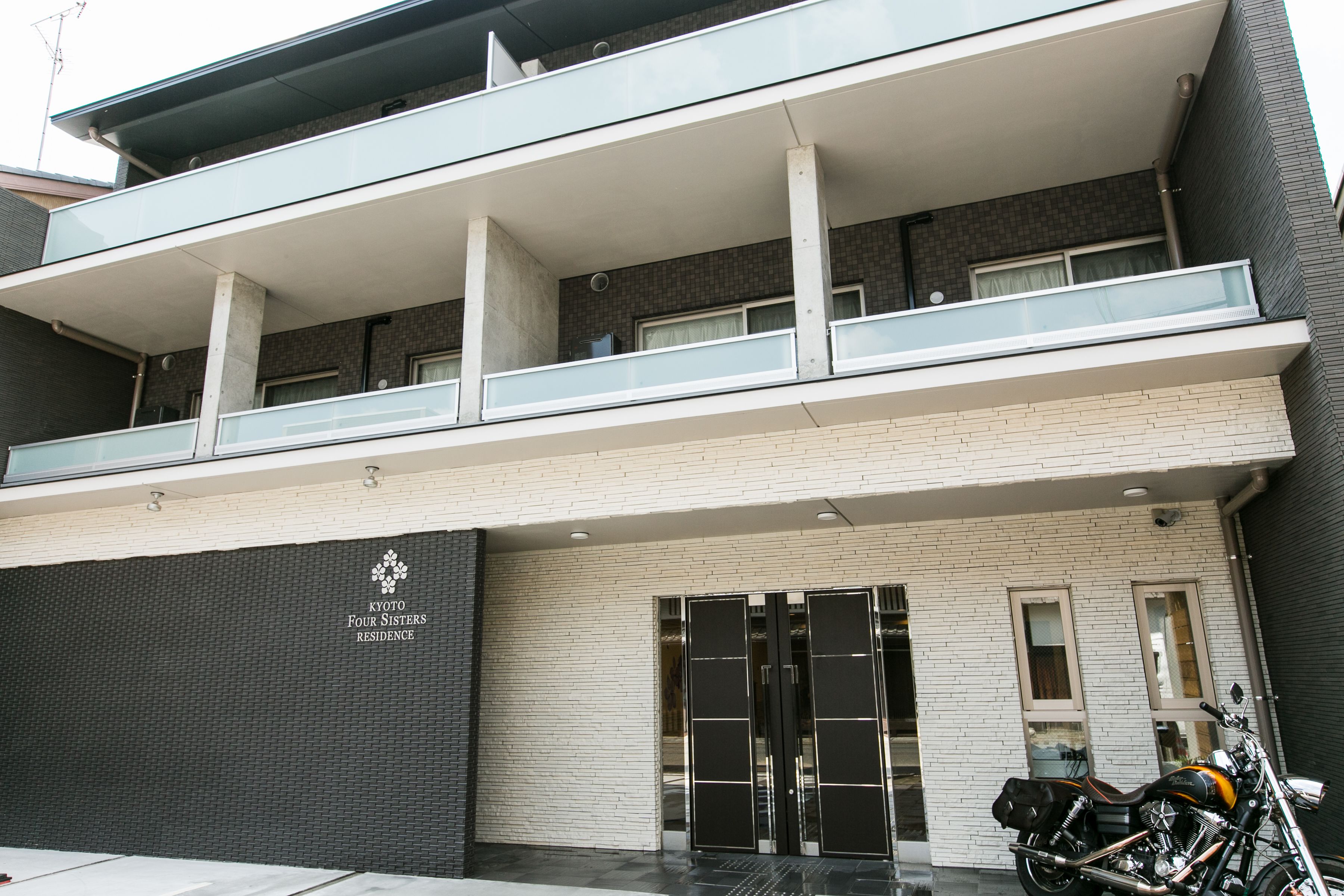 A modern building with a two-story entrance, glass railings, and a motorcycle parked outside.